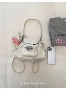 Detailed view of a sweet cream-white rucksack with a silver bow and bunny charm