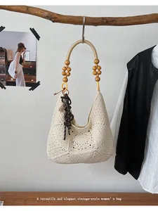 Handmade vintage beige crochet tote bag with wooden bead handle hanging on a branch