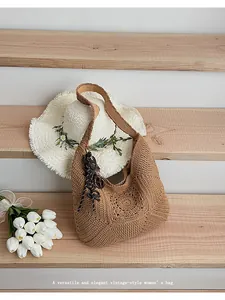 Vintage-style woven crochet shoulder bag displayed on wooden stairs with a sun hat