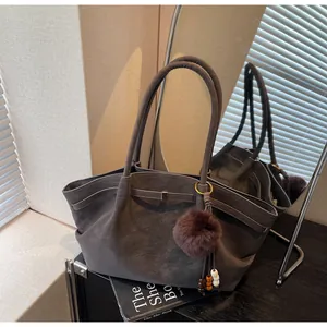 Detailed view of a vintage pleated tote bag in grey faux suede with a pompom charm.