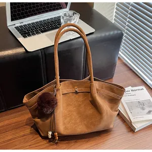Detail view of a large retro pleated brown tote bag in a lifestyle office setting