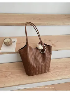 Detailed shot of vintage brown woven tote bag featuring long straps and cute bear charm