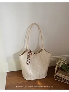 Close-up of a beige woven tote bag with a cute bear charm in a vintage room setting.