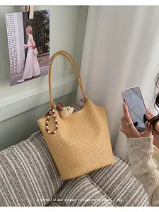 Close-up of a vintage yellow woven tote bag with a bear charm on a striped couch