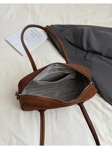 Interior detail of a brown retro underarm bag featuring a zipper pocket and grey lining