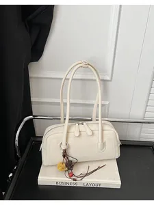 Detailed view of chic cream underarm pillow bag with elegant long handles and decorative charm.