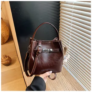 Dettaglio di una borsa a secchiello vintage in ecopelle marrone scuro con chiusura a scatto.