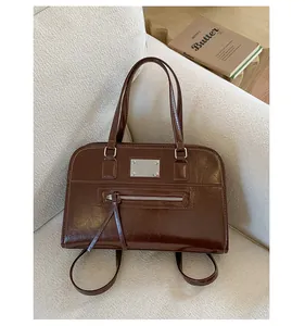 Detailed view of a dark brown polished leather convertible backpack placed on a soft textured sofa