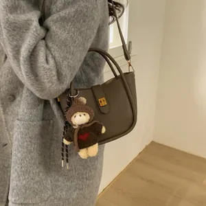 Vintage Lederbeuteltasche in Taupe mit süßem Bärenanhänger und grauem Wollmantel kombiniert