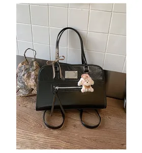 Detail view of a stylish black commuter backpack featuring a plush bear keychain and bow