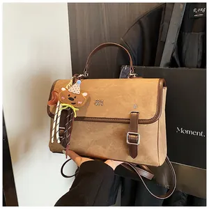 Detailed view of a vintage brown textured handbag with a cute bear charm for women's style.