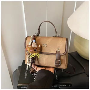 Detail view of a vintage brown textured handbag with a cute bear charm on a book.