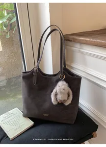 Primo piano della borsa tote retrò marrone capiente con un morbido ciondolo a coniglio.