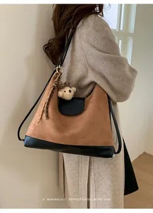 Detalle de la mochila de ante marrón retro con cuero negro y amuleto de oso