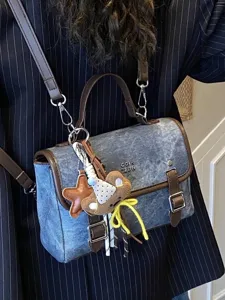 Fashionable denim satchel bag for women featuring brown leather trim and a cute bear charm