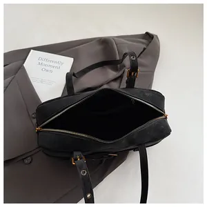 Detail view of black suede underarm bag interior showing spacious lining and gold zipper.