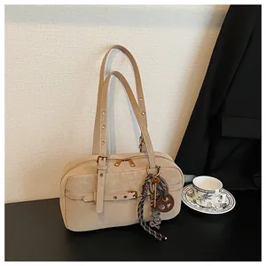 Elegant side view of a vintage beige underarm bag with stylish decorative charms
