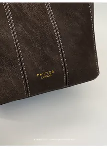 Detalle del bolso tipo cubo de cuero arrugado marrón con el logotipo PAN'TOR LONDON.