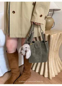 Bolso cubo retro de ante verde oliva con lindo amuleto de piel en escena.