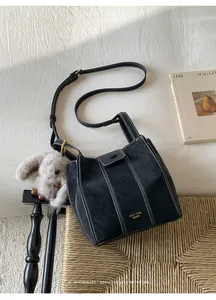 Elegante bolso de hombro tipo cubo negro con costuras en contraste en un interior