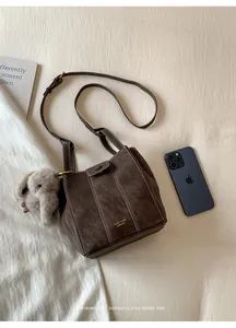 Bolso cubo vintage de ante sintético marrón oscuro con costuras y amuleto de conejo