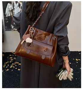 Large brown glossy vintage tote bag shown as a stylish shoulder bag on a model