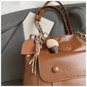Detailed view of brown vintage leather tote bag with heart charm and plush acorn accessory