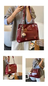 Detail view of a vintage wine red glossy tote bag with stylish charms and chain strap.
