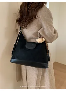 Bolso hobo retro de gamuza llevado por modelo con abrigo beige.