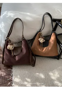Vista detallada de mochilas de ante marrón y tostado con aire retro y colgantes de oso