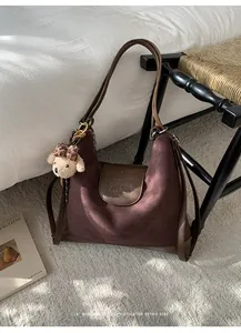 Primer plano de mochila retro en ante marrón con colgante de osito y textura de calidad.