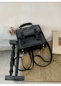 Dettaglio zaino da donna retrò nero e grigio su uno sgabello intrecciato rustico.