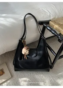 Bolso de hombro de gamuza negra retro con colgante de caniche en un entorno interior