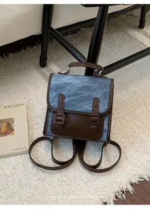 Vista dettagliata di uno zaino retro da donna in denim e pelle marrone su un tappeto bianco