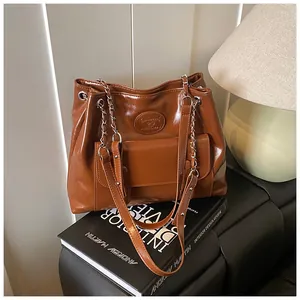 Detailed view of a vintage brown leather tote bag placed on a black interior design book