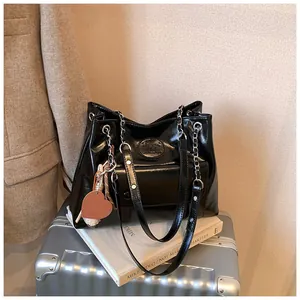 Detail of retro black faux leather tote bag with silver chain straps and heart charm
