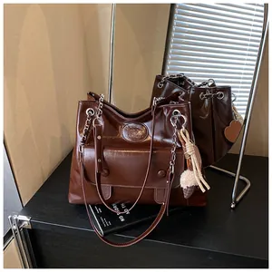 Detail view of a vintage dark brown glossy tote bag with chain strap and charms