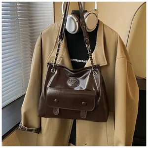 Large vintage dark brown tote bag with front pocket shown on a stylish outfit