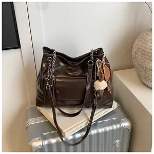 Large dark brown glossy retro tote bag with plush charm on a silver suitcase detail