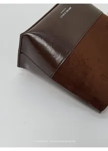Close-up detail of retro brown suede and shiny leather patchwork on minimalist tote bag