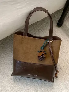 Vintage brown suede and leather patchwork tote bag for women featuring a floral charm accessory