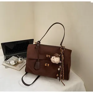 Vintage brown suede commuter tote bag with decorative plush charm in workspace setting