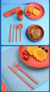 Close-up of orange wheat straw cutlery set including knife and fork with a textured plate