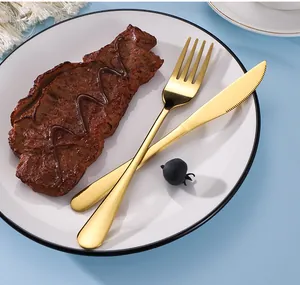 Elegant close-up of golden stainless steel fork and knife set on a white ceramic plate