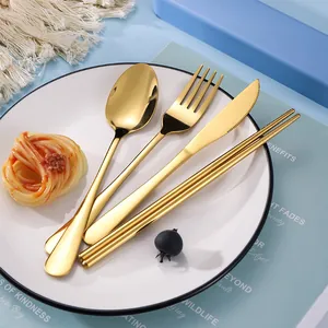 Golden stainless steel cutlery set with spoon, fork, knife and chopsticks on a plate