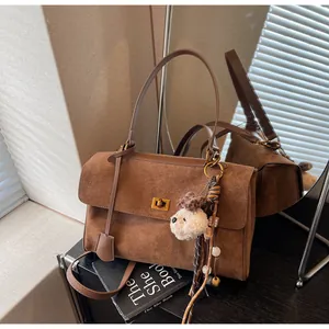 Close-up of vintage brown suede shoulder bag with cute plush puppy charm on black desk