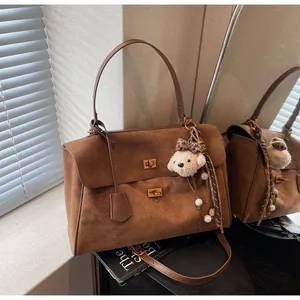 Detailed view of the brown faux suede vintage handbag with a cute white puppy charm.