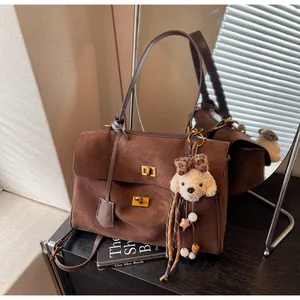 Detailed macro view of brown suede texture and cute puppy charm on a retro crossbody bag