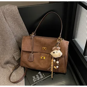 Close-up view of retro brown matte suede handbag with a cute bear charm and gold clasps
