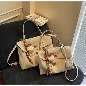 Detailed view of beige suede handbags featuring decorative bear charms on a textured sofa